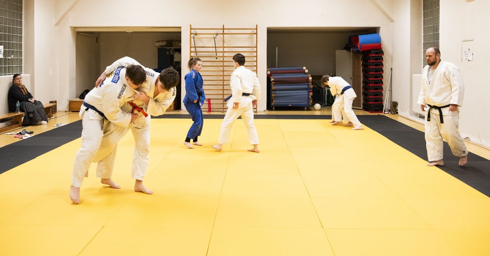 Zwei Judoka des Vereins Kaizen beim Training. Trainer und weitere Judoka des Vereins im Hintergrund